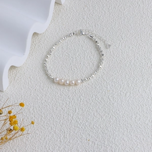 Detail view of natural freshwater pearl necklace with geometric silver chain on a white surface