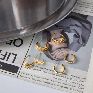 Close-up of three pairs of 18K gold-plated C-hoop earrings with textured and crystal details
