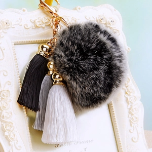 Close-up of grey and black faux fur pompom keychain with white and grey tassels