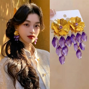 Detail showing gold flower earrings with purple tassel beads and resin crystal accents