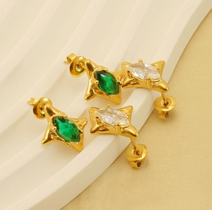 Detail view of 18k gold star earrings with emerald and white zircon gemstones