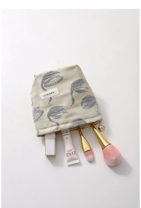 Detail of swan jacquard makeup bag showing petal-shaped zipper and compact interior storage