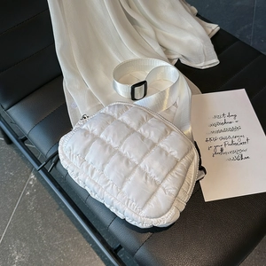 Detail of white quilted crossbody bag with adjustable wide strap and metallic chain link