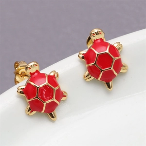 Macro view of gold turtle stud earrings with vibrant red enamel shell and hexagonal pattern