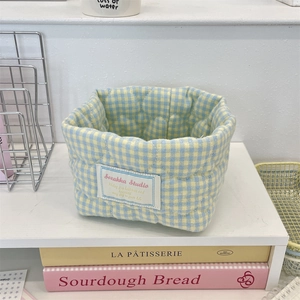 Detailed shot of a blue and yellow plaid quilted fabric storage bin on a white shelf
