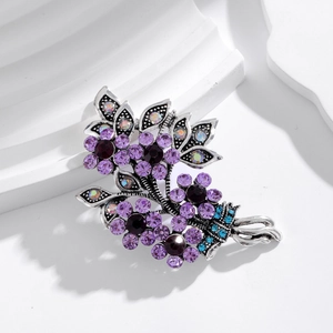 Vintage crystal bouquet brooch with purple rhinestones on a white architectural stand