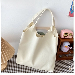 Detailansicht einer minimalistischen cremeweißen Canvas-Tasche auf einem Holz Tisch