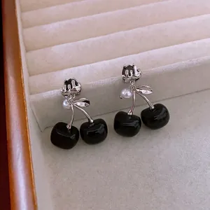 Orecchini a ciliegia in argento con sfere nere e perle su vassoio beige per gioielli