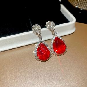 Macro shot of silver vintage earrings with red teardrop gems and star-shaped stud details