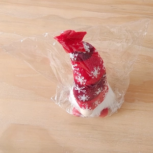 Close-up of Christmas gnome with red snowflake knit hat in clear plastic packaging