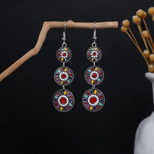 Close-up of Bohemian tiered drop earrings with colorful floral beads on wooden branch