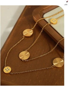 Close-up of golden titanium steel sweater chain with sunburst and diamond-set pendants