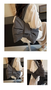 Detail view of dark grey padded nylon bag featuring a stylish bow and wide shoulder strap