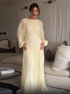 Detailed view of pale yellow pleated long sleeve maxi dress with elegant ruching texture