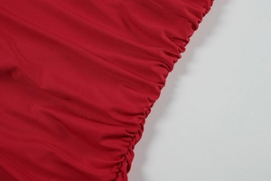 Detailed macro view of the ruched red elastic fabric texture on a slim-fit summer dress