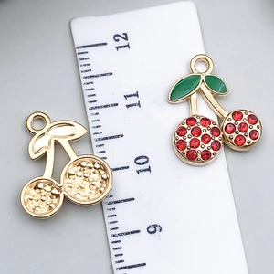 Macro detail of red rhinestone cherry pendants with ruler showing size measurement