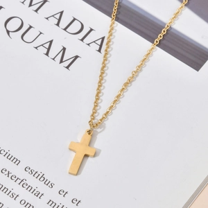 Vue macro d'un collier pendentif croix doré avec placage 18K sur chaîne en acier