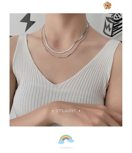 Detail of a double-layered stainless steel snake chain necklace worn on neck