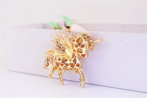 Détail d'un pendentif pégase doré avec motifs de cœurs évidés sur un récipient blanc