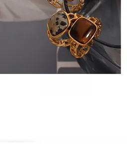 Detail of double-layer C-shape earrings with chain design and square stone inlays