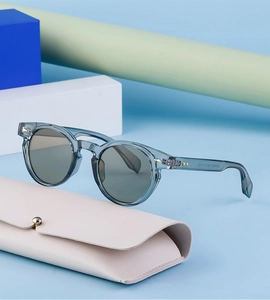 Detail view of oval sunglasses with transparent blue frame and beige leather case