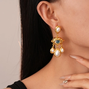 Détail de la boucle d'oreille baroque avec œil doré et perles en cascade