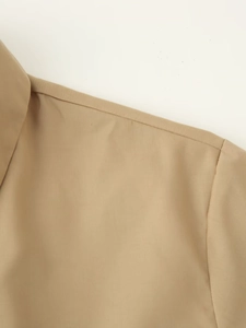 Gros plan sur les coutures fines et le tissu tissé kaki lisse sur l'épaule de cet ensemble