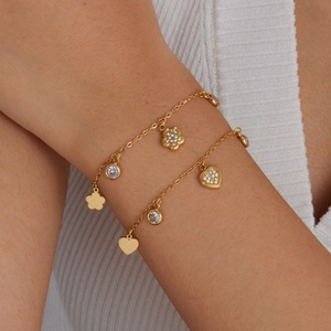 Gold-plated stainless steel bracelet with heart and floral charms on a model's wrist