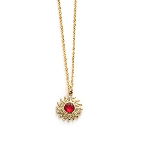 Detail of sunburst pendant with a faceted red stone and delicate gold cross chain