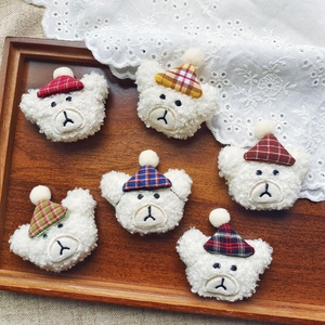 Plush teddy bear heads with plaid hats on a wooden tray for DIY hair accessories