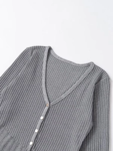 Close-up of gray knit cardigan featuring V-neckline, ribbed texture and button detail