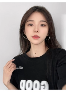 Close-up of minimalist silver twisted hoop earrings worn with a black crew neck T-shirt