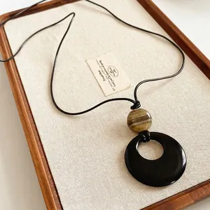 Collana vintage con pendente ad anello in agata e perla marrone su vassoio di lino