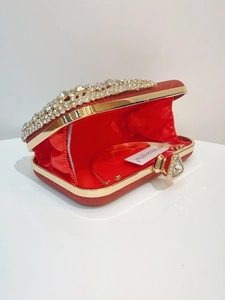 Detail of red sequin evening clutch featuring sparkling rhinestones and gold metal trim