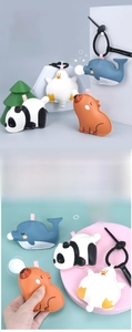 Detail showing hand squeezing animal cartoon keychain to blow a bubble for stress relief