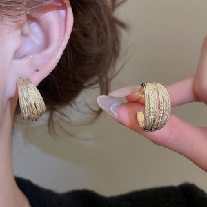 Detailed view of gold multi-layer C-shaped earrings with fine textured metallic finish