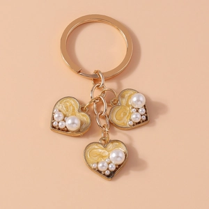 Detailed view of heart-shaped charm keychain with yellow enamel and white pearls