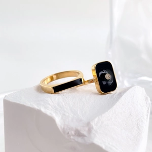 French style gold ring with black enamel rectangle and central gem on white stone