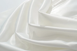 Dettaglio del tessuto in raso bianco con texture lucida ed eleganti pieghe morbide