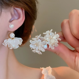 Close-up of white flower and pearl earrings with elegant tassel details and petal charms