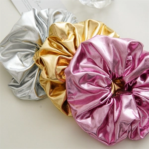 Set of shiny metallic scrunchies in silver, gold, and pink with reflective surface