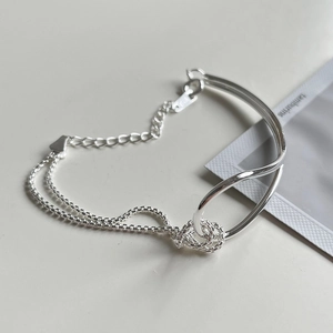 Detail of minimalist S925 sterling silver knotted bracelet with polished metal texture