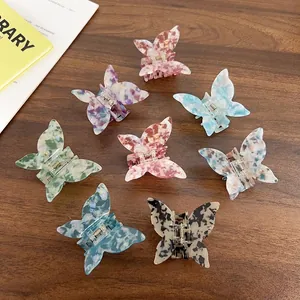 Set of seven colorful butterfly hair claws with iridescent marble textures on wood