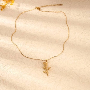 Close-up of a 18K gold rose pendant necklace on textured warm paper background