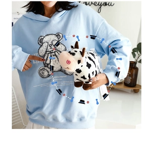 Close-up of a cute plush cow doll and cartoon crossbody bag with soft faux fur texture