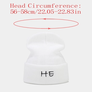 Close-up of white knitted beanie featuring HE letter embroidery and size scale markings