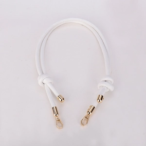 Close-up of white microfiber tubular shoulder strap with gold lobster clasps and knots