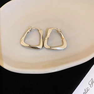 Detailed macro shot of silver geometric earrings on a minimalist ceramic tray