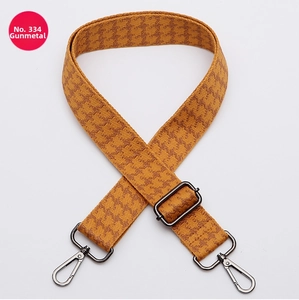 Detail of adjustable wide bag strap with yellow houndstooth pattern and gunmetal hardware