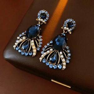 Vintage gold baroque earrings with deep blue gemstones and pearls on brown leather background